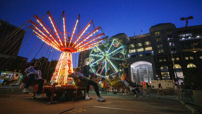 The Musical Chairs ride and Ferris wheel light up the East Stadium Plaza during the 2022 Cornstock Festival.