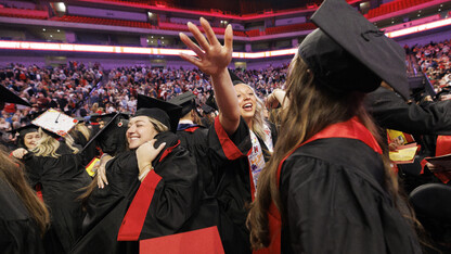 Graduates Anna Dukart and Paxtyn Dummer hug their fellow graduates at commencement.