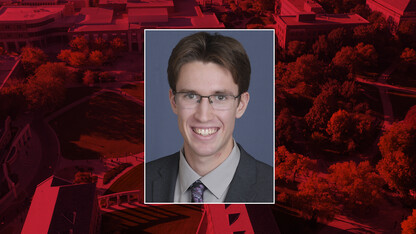 Color photo of Brian Beach on a red campus background