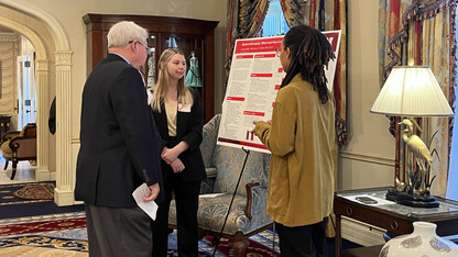 Seniors Lauren Behnk (center) and Meklit Aga (right) present their research poster to State Sen. Rick Holdcroft (left).