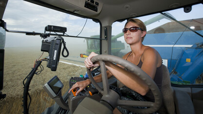 Mikki Briggs pulls a grain wagon with a tractor as the Briggs Harvesting crew works its way through a wheat field west of Grant, Nebraska, in this file photo.