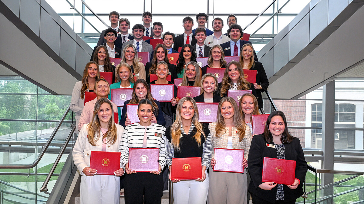 Thirty-two Husker students pose on a staircase in Howard L. Hawks Hall, holding certificates.