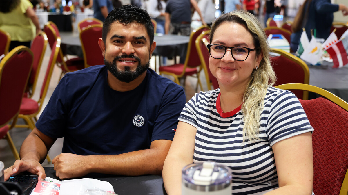 A man and woman, seated at a table, smile for a photograph during the 2024 Nebraska Small Business Conference in Lincoln.