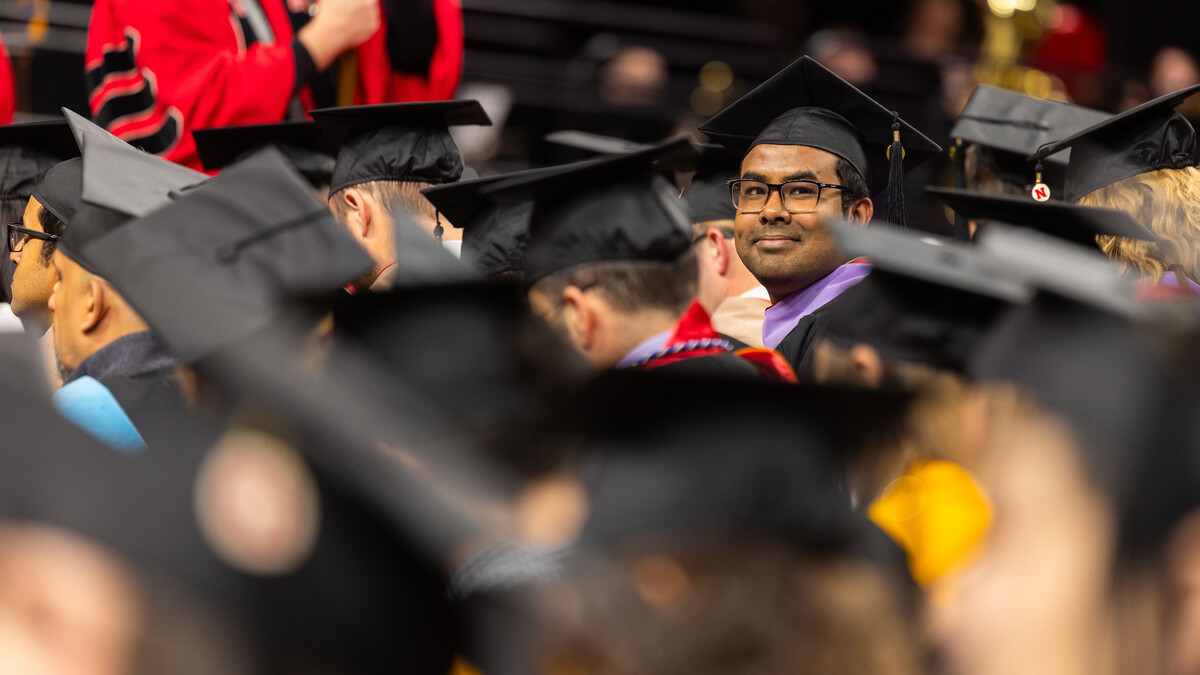 Md Asaduzzaman Noor, seated among fellow graduates, looks for family and friends in the audience during the graduate and professional degree ceremony Dec. 19 at Pinnacle Bank Arena.