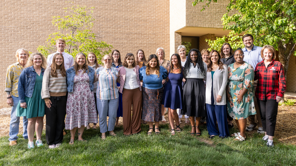 Twenty-one people, mostly women, pose for an outdoor group photo.