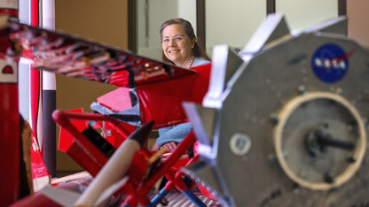 Karen Stelling is a professor of practice in mechanical and materials engineering. She is the adviser of the Aerospace Club, which is working on a satellite project with NASA, through a student grant project. She poses in the lobby of Othmer Hall with a display of Nebraska Engineering aerospace engineering projects. 