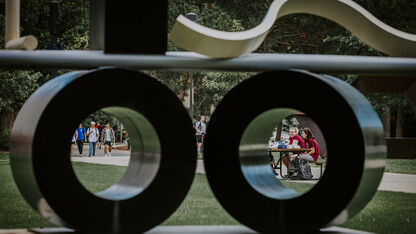 Students framed in circles created by the campus sculpture "Balanced/Unbalanced Wheels No. 2."