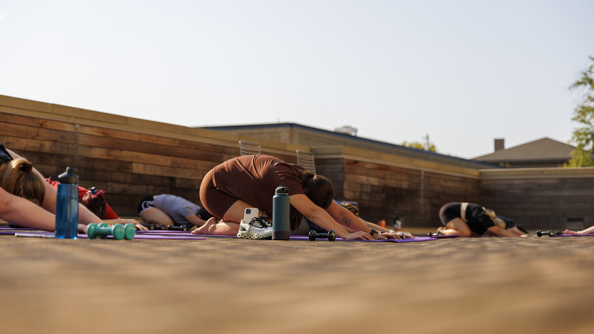 A participant finds child's pose in an outdoor group fitness class.