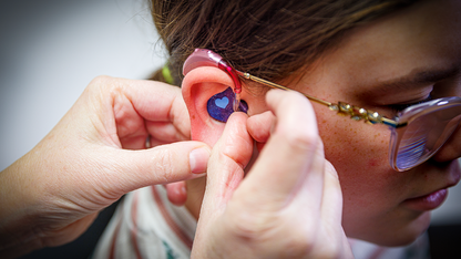 Ear with hearing aid being checked by audiologist