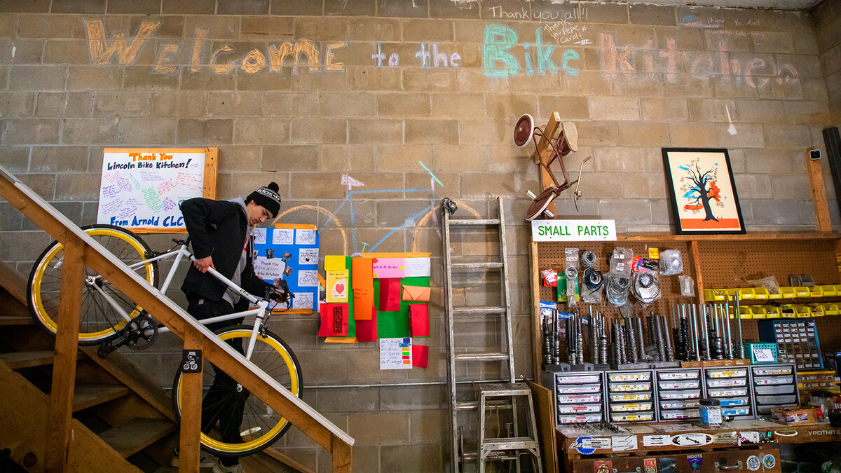 Jacob Dalton carries a bike down from storage in the Lincoln Bike Kitchen.