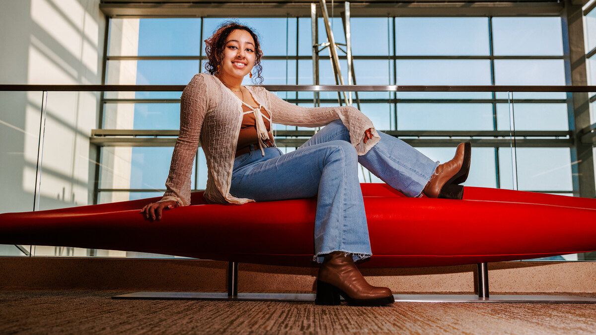 Ale poses for a photo on a bench in Hawks Hall