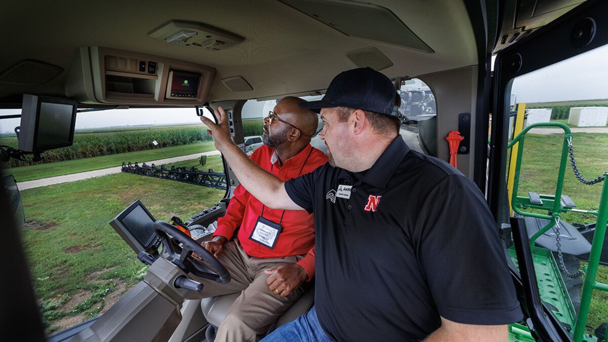 Chancellor Rodney Bennett rides in the cab of a John Deere sprayer.