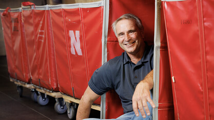 Larry Shippen sits near a red container used for student move-in