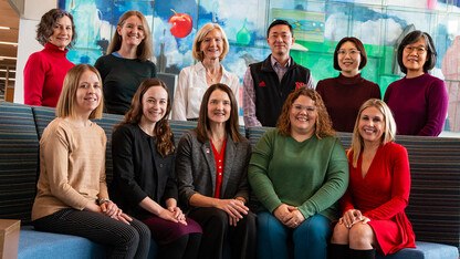 Research team photo with members sitting and standing by a wall.