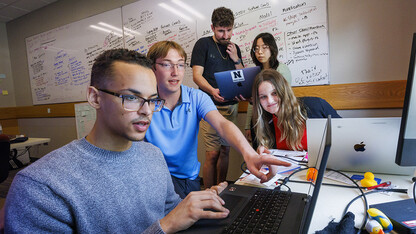 Dyslexico team members Tristan Curd, Nick Lauver and Bridget Peterkin look over data while, in back, Santiago Giraldo and Victoria Chin compare notes.