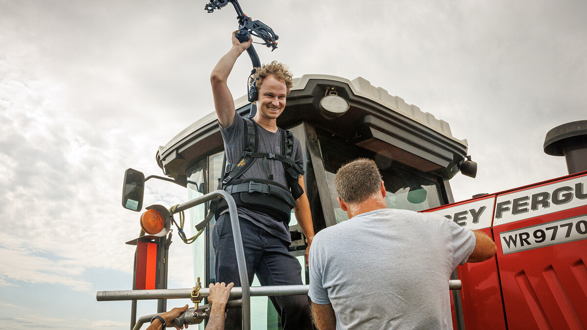 Carter Knopik, a 2019 UNL graduate, smiles as he stands on a tractor during the filming of the university's new institutional spot.