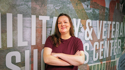 A woman stands in front of a mural.