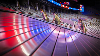 Army ROTC cadets Michaela Guzman, Chloe Johnston and Ella Valleley climb the steps in west stadium as the electronic graphics are reflected in the stair well covers.