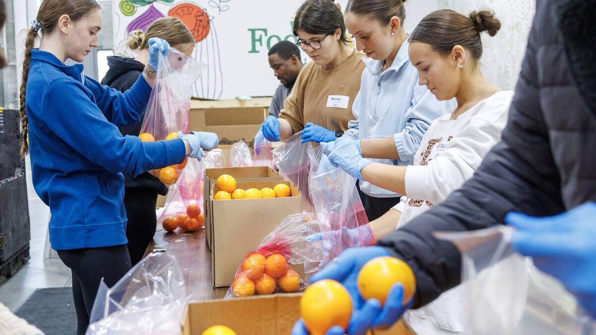 Students place oranges into distribution bags for the Food Bank of Lincoln.