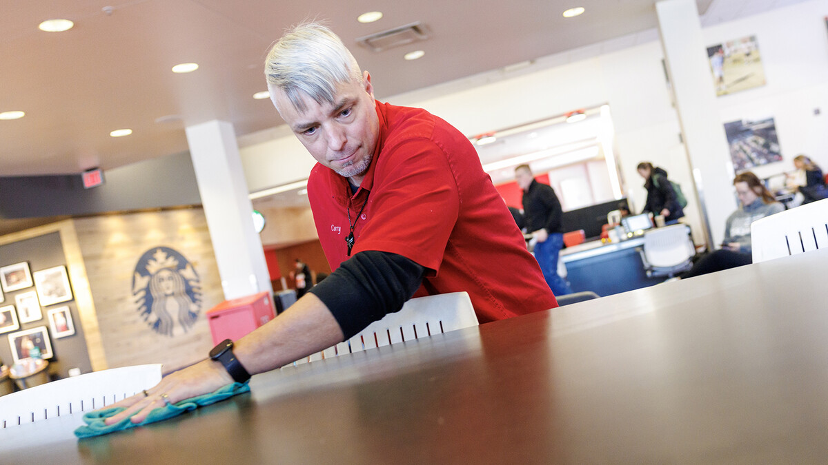 Cory Densberger, a hospitality service associate in the Nebraska Union, wipes a table clean in the food court. Densberger's outgoing personality has positive connections with students, faculty, staff and campus visitors. He's also been honored with three Parent's Association awards, which require nominations from students.