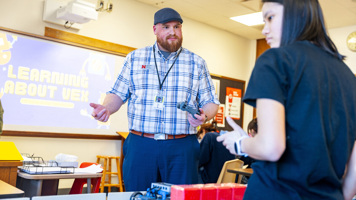Zach Short, project director for Educational Talent Search, guides Lily Tran, a sophomore, through using the controls to make the robot move.