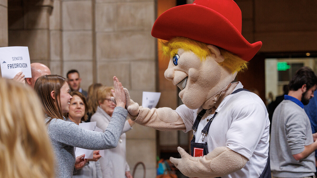 Herbie high fives Liz Husmann of UNMC during the I Love NU Day Celebration in the capitol Rotunda.