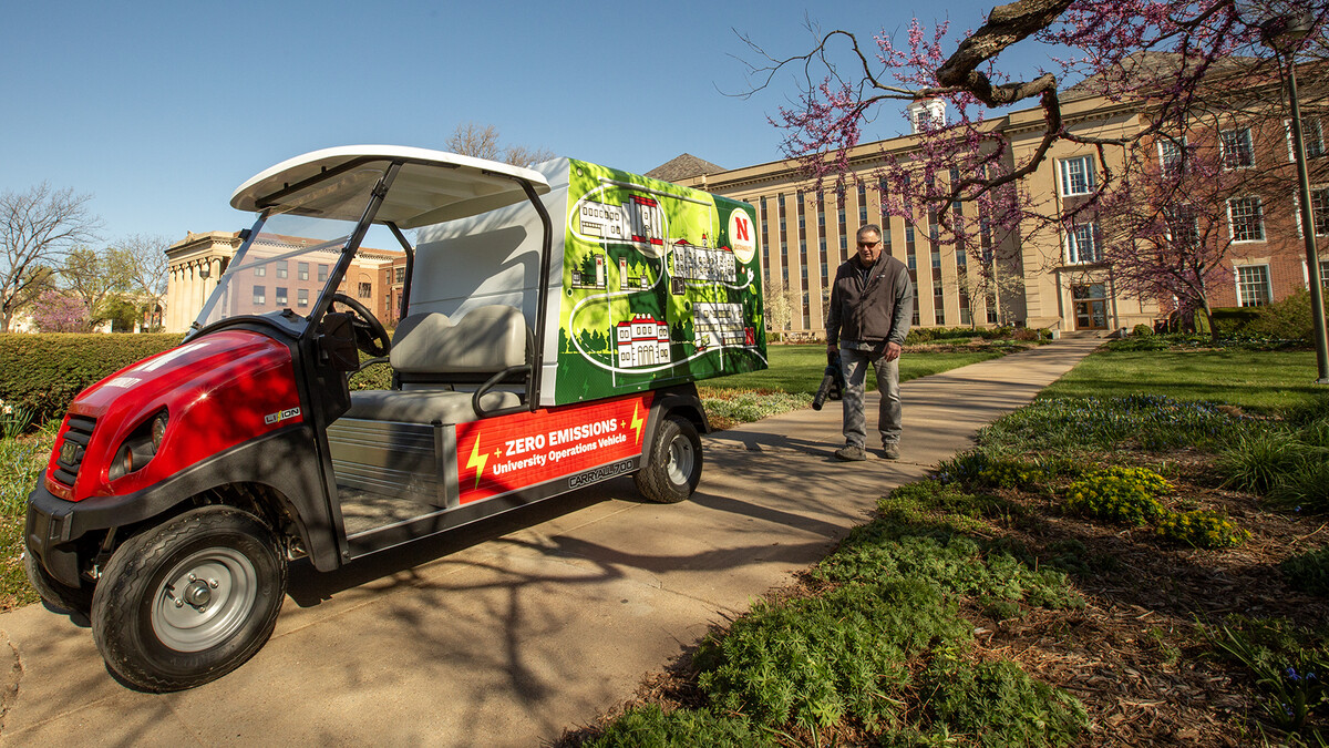 Jeff Culbertson, director of landscape operations, operates a battery-powered leaf blower near by Love Library with Landscape Services new electric vehicle in the foreground.