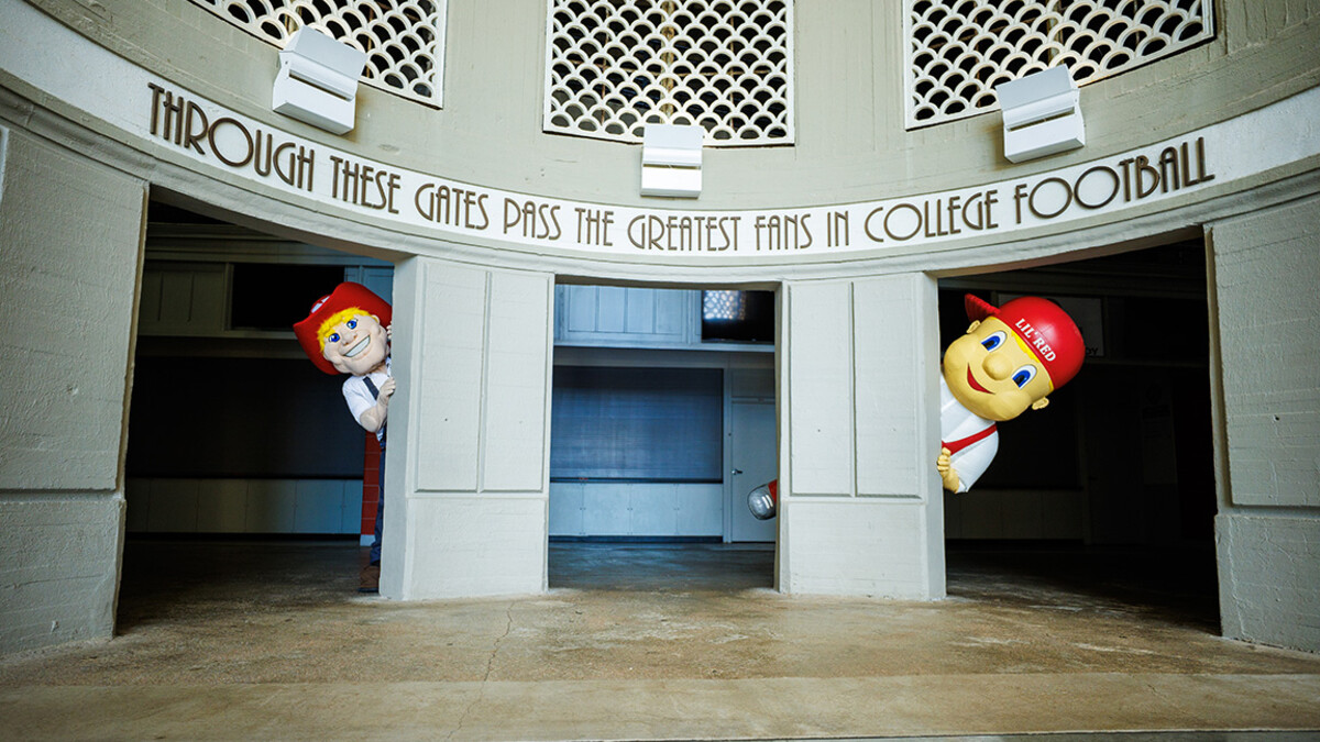 Herbie Husker and Lil' Red peek out between columns in Memorial Stadium.