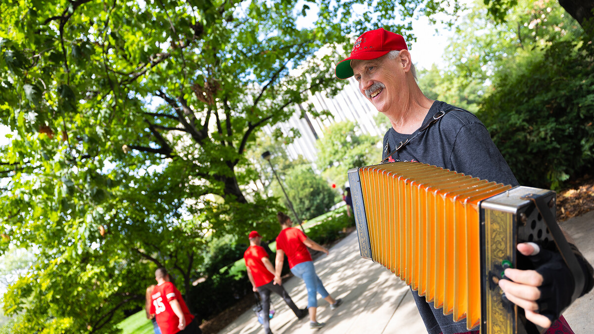 Chris Sayre plays his accordion during as fans walk by Sheldon Memorial Art Gallery the 12th Street mall.