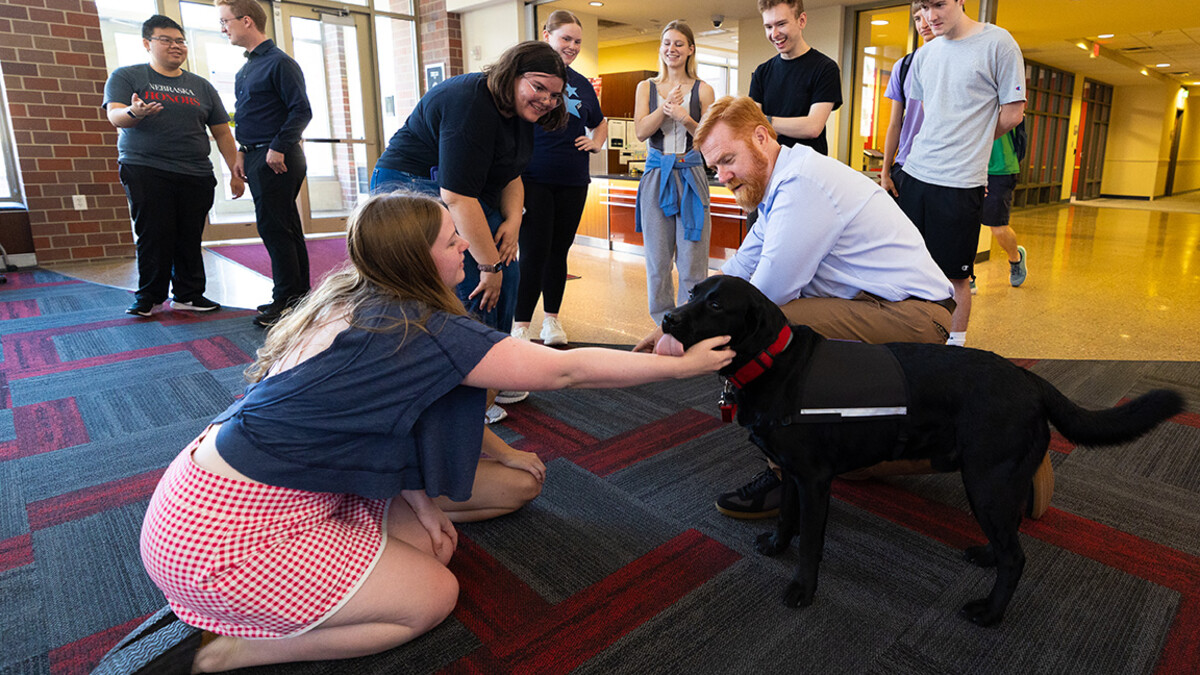 Students in the Honors Program smile as Jax, the program's therapy dog, gives a kiss to Emily Hughes, a first-year student majoring in forensic biology and pre-med.