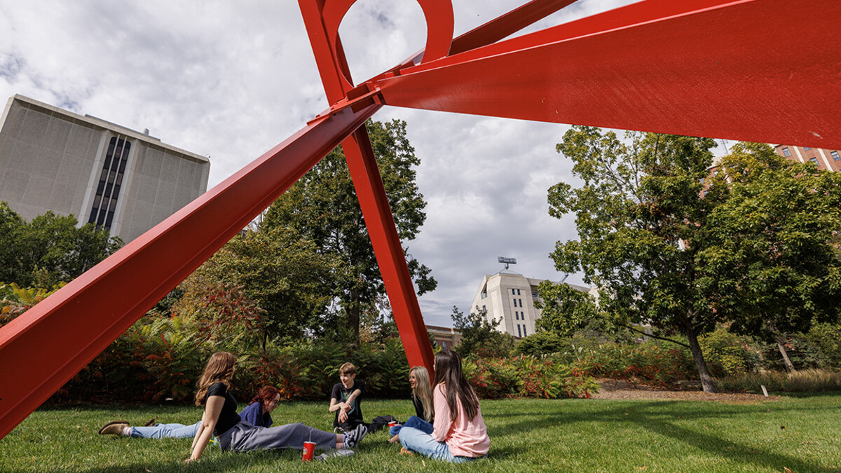 Fall glory: Mackenzie Frederick, from left, Sydney Schmid, Dominick Mangano, Carly Peterson, and Surina Burlington sit underneath “Old Glory” during a sunny fall afternoon. Oct. 20, 2025.