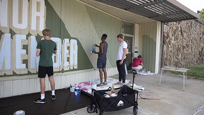 Students from Associate Professor of Art Sandra Williams’ University Honors seminar Graffiti Revolution help Shawn Dunwoody (second from left) paint his mural at the Veterans of Foreign Wars at 2431 N. 48th St. Photo by Eddy Aldana.