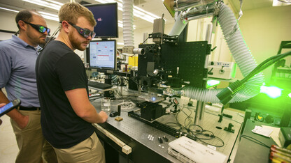 Craig Zuhlke, a research assistant professor, and Aaron Ediger, a graduate research assistant, watch as a laser modifies a small sample of metal. The research, led by Nebraska's Dennis Alexander, is modifying metal surfaces to mimic biological properties, including shark skin. The research is used primarily for defense and industrial purposes.