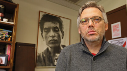 Scott Anderson, professor of music, mimics the look of Bob Dylan in the poster in the background. Anderson is teaching an honors course that focuses on Dylan, who earned the Nobel Prize for Literature on Oct. 13. 