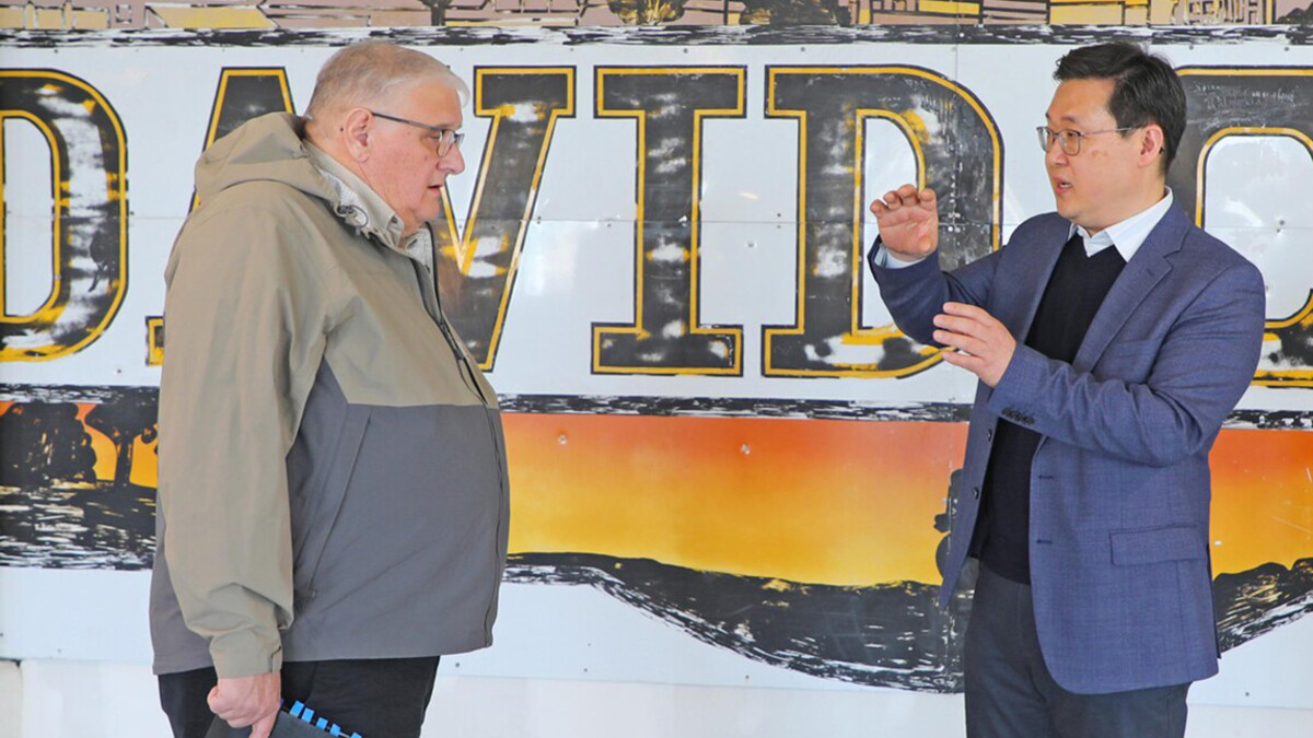 Two people speak in front of a mural speling out David.