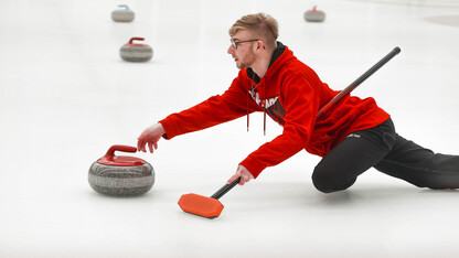 Brett Johnson slides a curling stone Saturday during the club team's bonspiel at the Breslow Hockey Center.