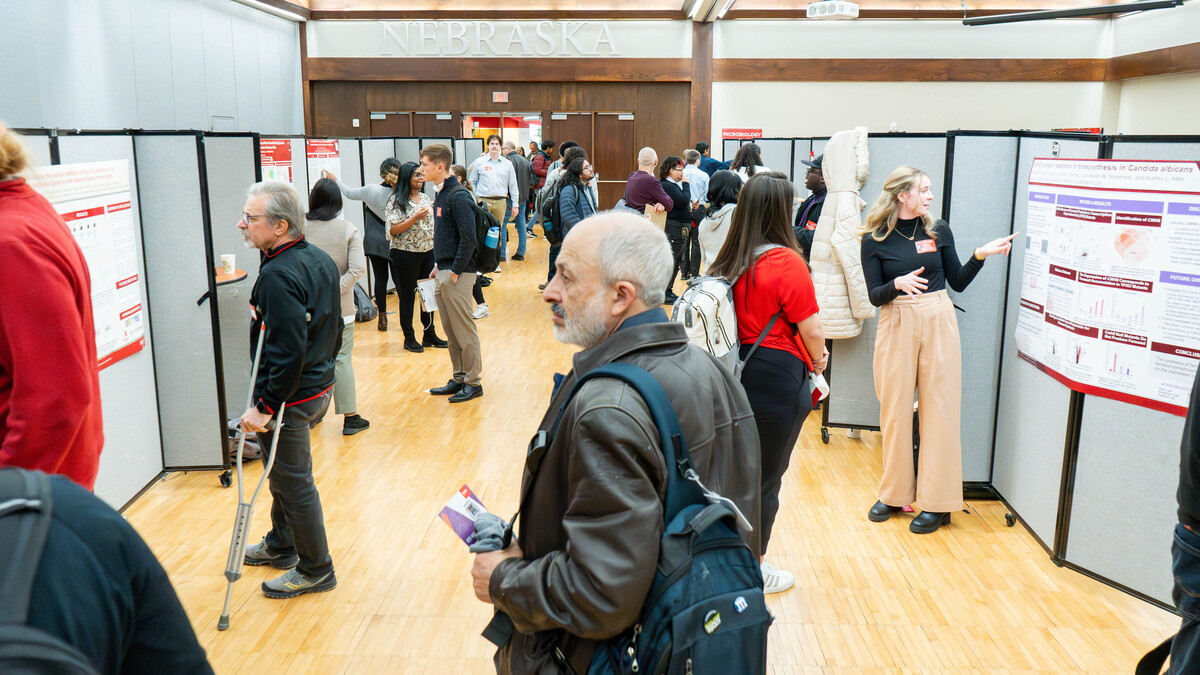 A crowd roams as microbiology students give presentations alongside posters.