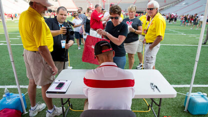 Nebraska head coach Mike Riley signs an autograph during UNL's 2015 Fan Day at Memorial Stadium.