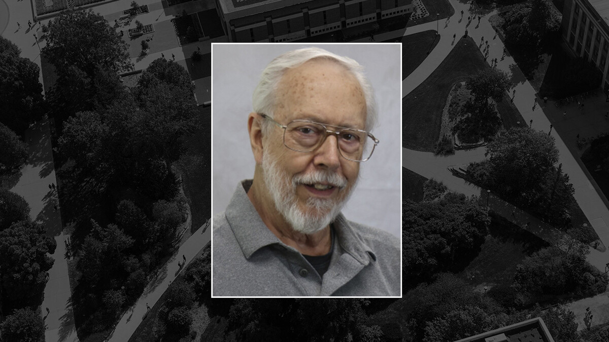Richard Dienstbier, a white man with short white hair and a white beard, smiles in square, thin-framed glasses, in a grey shirt.