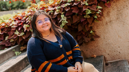 Dulce Isabel Garcia sits in front of a wall of greenery on campus.