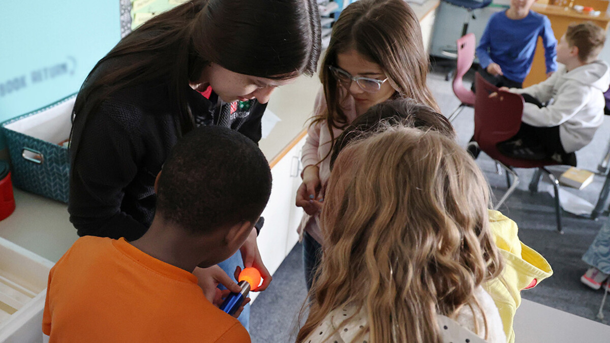 Extension Assistant Madelaine Polk “candles” an egg after seven days of incubation for third-grade students at Trinity Lutheran