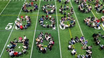 An aerial view of students seated in circular arrangements on Tom Osborne Field