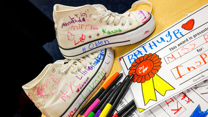 A pair of white Converse shoes adorned with the multicolored names of kindergartners taught by Husker senior Crandall Blake