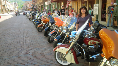 Nebraska's Pat Wemhoff stands next to one of her family's motorcycles on the main drag in Deadwood, South Dakota. Wemhoff became interested in riding motorcycles after meeting her husband.