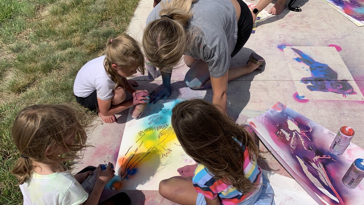 Students from the Alliance Recreation Center create spray chalk animals as part of the Stay Wild community arts project, led by Associate Professor of Art Sandra Williams.