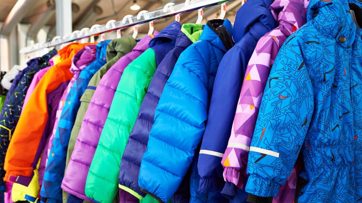 Brightly-colored children's coats hang on hangers.