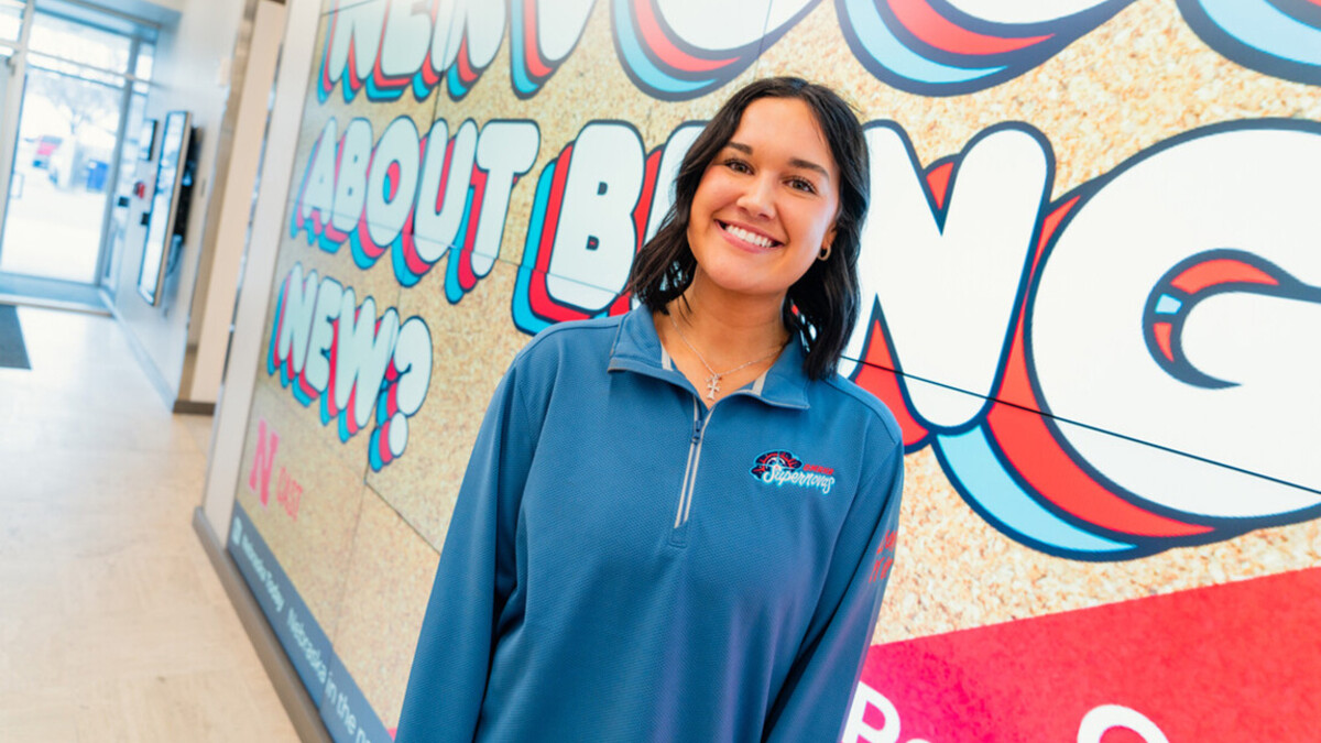 Maddie Meyerle stands in front of a mural, wearing a blue shirt.