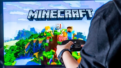 A screen shows Minecraft title card as a player holds a game controller