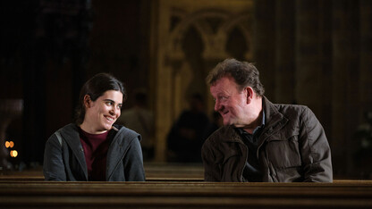 Scene from "The Old Oak" showing the pub owner standing across the bar and talking with a young Syrian refugee.