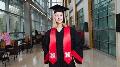 Sarah Hindman is photographed in her graduation cap and gown at Hawks Hall.